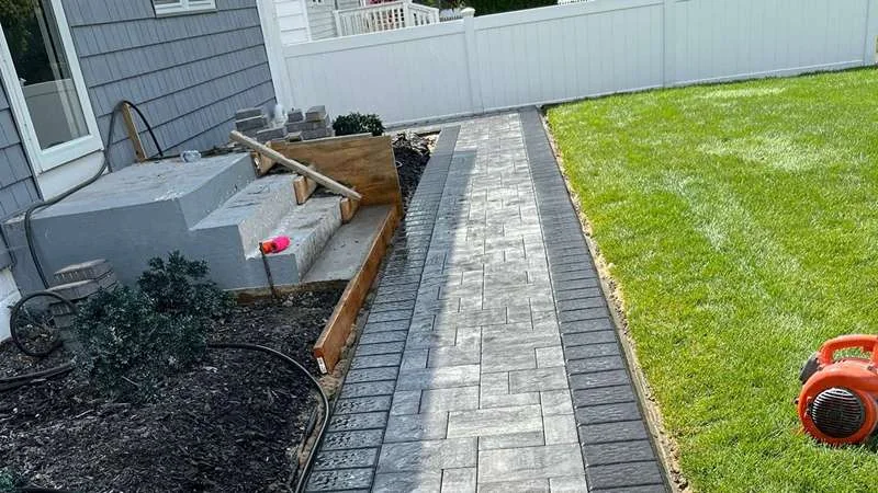 Paver walkway bringing the path along the side yard, with garden beds beside it.