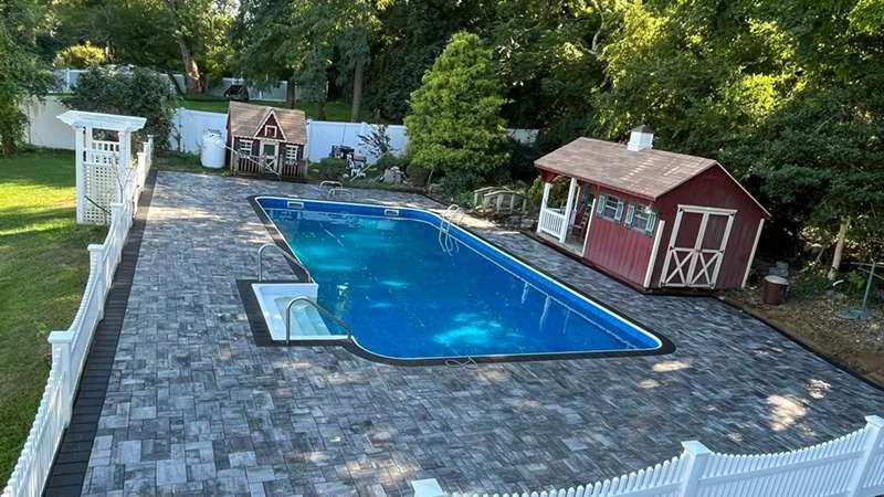 Large-format pavers laid around the pool, cut tight to the coping.