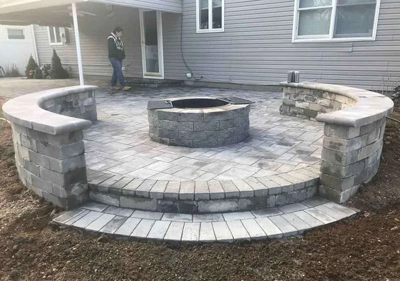 Fire pit built into the patio, framed by two curved block seat walls.