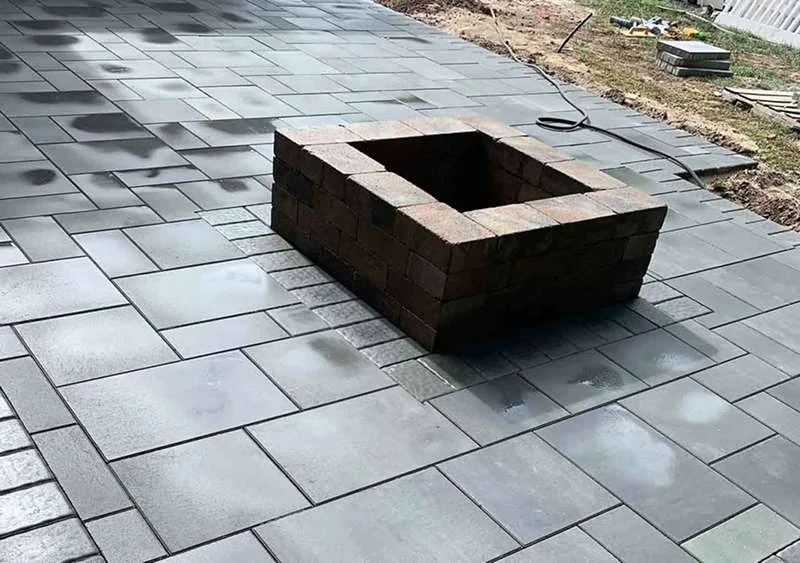 Raised fire pit insert set into large-format pavers and finished square.