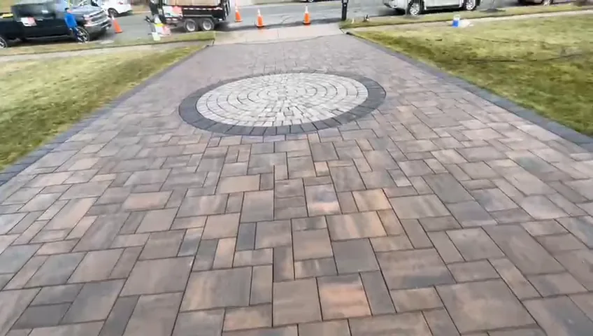 Wide paver driveway with a decorative circular medallion set into the paving.