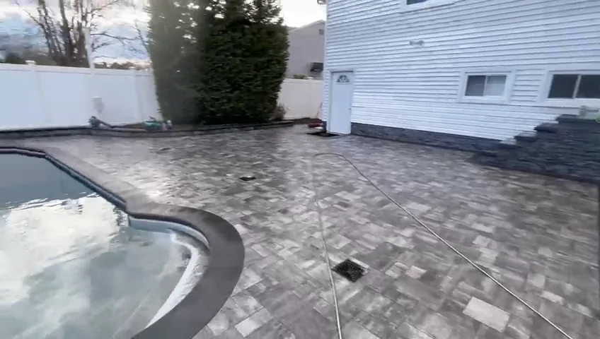 Paver pool deck running along a white vinyl privacy fence.