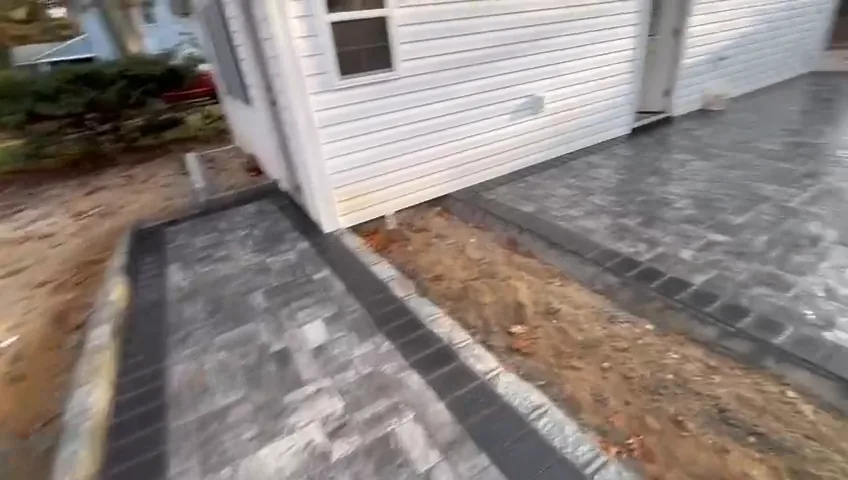 Dark grey paver walkway running along a gravel strip beside the house.